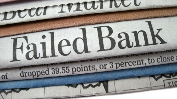 A stack of newspapers, one that reads "Failed Bank" in large print.