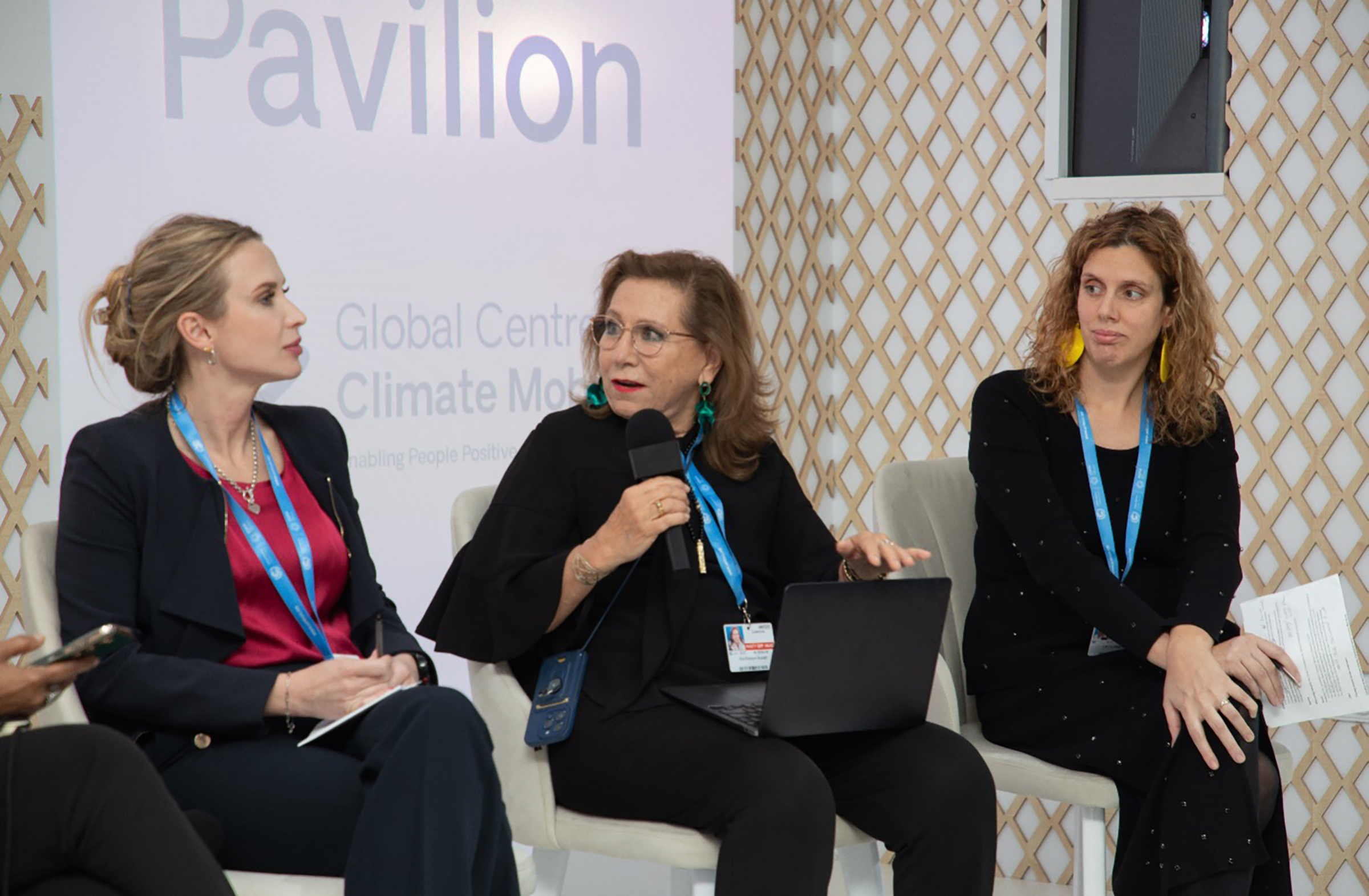 Three seated women, all with conference badges