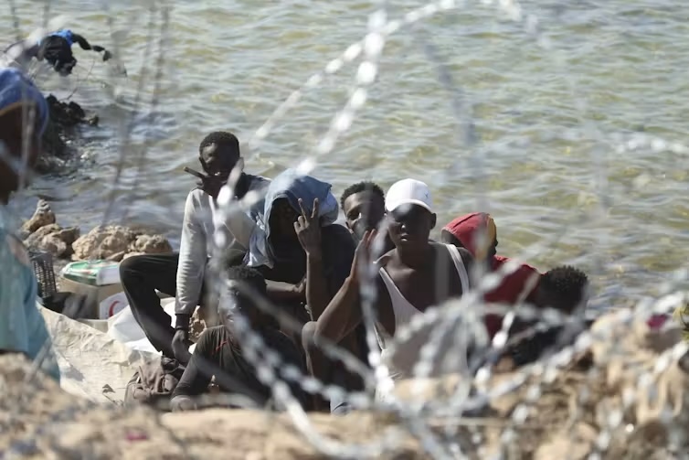 Migrants gather in an area near the Libyan-Tunisia border, as Libyan security forces and Libyan Red Cross workers distribute food aid to them.