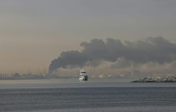 A yacht sails past a plume of smoke rising from the port of Jebel Ali following a reported Iranian strike in Dubai on March 1, 2026.