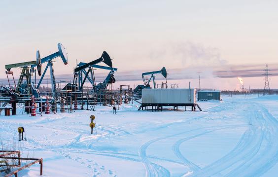 Oil Field. Winter industrial landscape with an oil pump and torch in the background. 