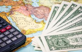 Money and a calculator rest on top of a map of the Middle East.