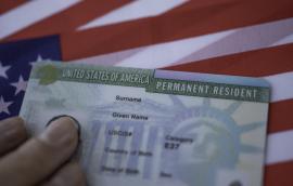 A permanent resident card rests on a U.S. flag.