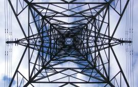 This photo shows an upward view of a transmission tower.