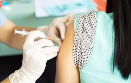 A woman receives a vaccine in her left arm.