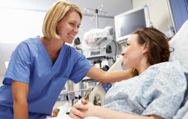 A nurse and a patient smile at each other.