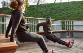 Two individuals in masks doing tricep exercises outdoors.