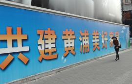 Person walks alongside large banner with Chinese characters