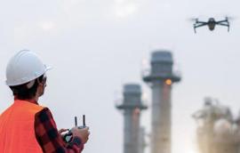person in safety vest flying drone near power plant
