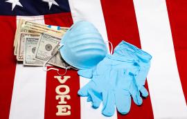 A mask, gloves, money, and letters spelling "vote" lie on a flag of the United States.