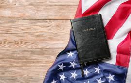 Holy Bible and American flag on wooden background