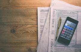 tax forms on table with calculator and pen on top
