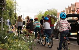 Kids on bikes being led by adults on sidewalk