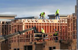  A crew of construction workers atop wooden structures, building a multistory apartment complex in East Mesa, Arizona.