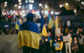 Person standing in crowd wearing Ukrainian flag