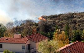 Wildfire erupts near houses on a hill