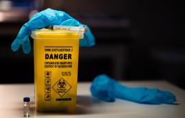 Gloves and syringe on top of sharps container