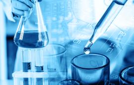 Hand of scientist holding flask with lab glassware and test tubes in chemical laboratory background.