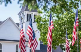 American flags waving outside old white church building