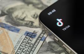 TikTok app on smartphone screen with dollar background