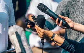 Reporters hold up microphones