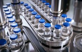 Closeup of ampules are being filled with vaccine and closed with blue caps.