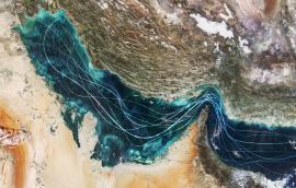 Satellite view of the Persian Gulf and Strait of Hormuz with glowing blue lines symbolizing naval traffic and strategic maritime routes amidst geopolitical tensions and regional conflict in Iran.