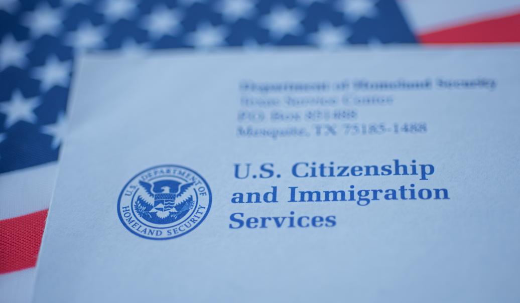 An envelope from the U.S. Citizenship and Immigration Services rests on the U.S. flag.