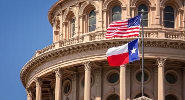 A close-up of the Texas Capitol building and the U.S. and Texas flags.