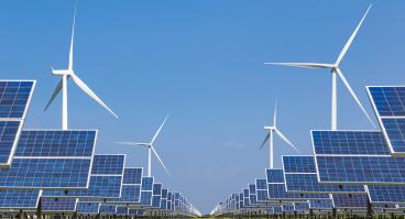 Windmills and solar panels in a grass field.