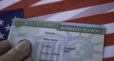 A permanent resident card rests on a U.S. flag.