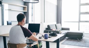 A person doing remote work on their laptop from their house.