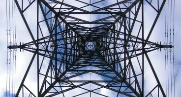 This photo shows an upward view of a transmission tower.