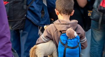 A refugee boy holds a stuffed animal.
