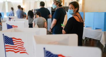 Woman with mask waiting in line to vote in a U.S. election.