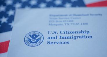 An envelope from the U.S. Citizenship and Immigration Services rests on the U.S. flag.