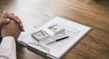 Wad of cash on top of a contract