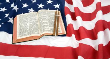 A Bible and the Christian cross on top of an American Flag.