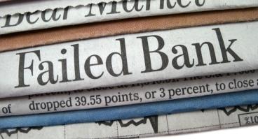 A stack of newspapers, one that reads "Failed Bank" in large print.