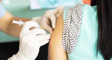 A woman receives a vaccine in her left arm.