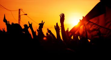 Hands raise up against a sunset.