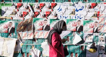Woman in Iran stands in front of election posters