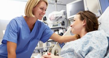 A nurse and a patient smile at each other.