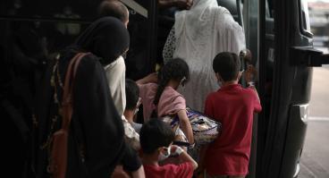 A family of Afghan refugees board a bus.