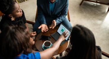 Four people discussing business around a table with coffee.
