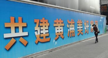 Person walks alongside large banner with Chinese characters