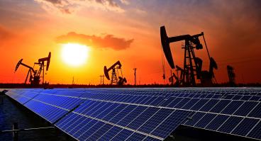 Clean energy transition concept: Solar panels and oil pump jacks share a field