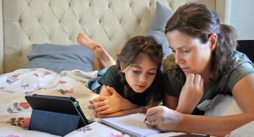 A mother teaches her daughter at home.