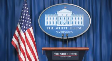 Podium speaker tribune with US flags and sign of White House