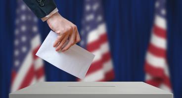 Voter holds envelope in hand above vote ballot